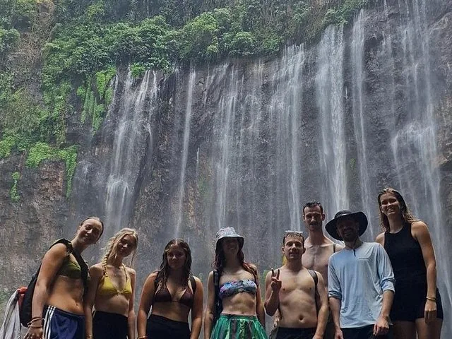 group of friends posing together in front of Tumpak Sewu Waterfall