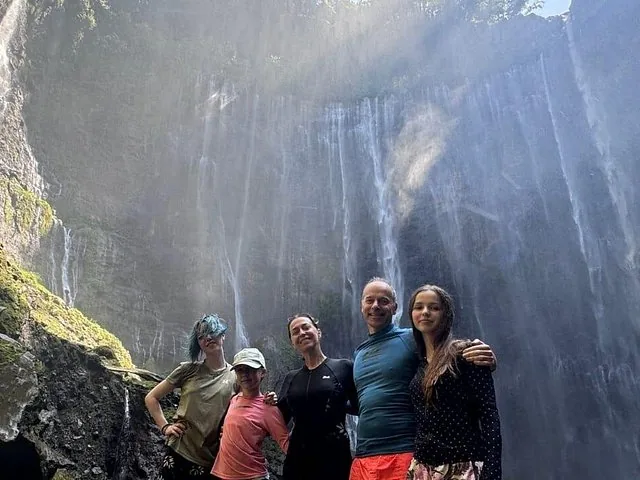 family standing together at the base of the impressive Tumpak Sewu Waterfall