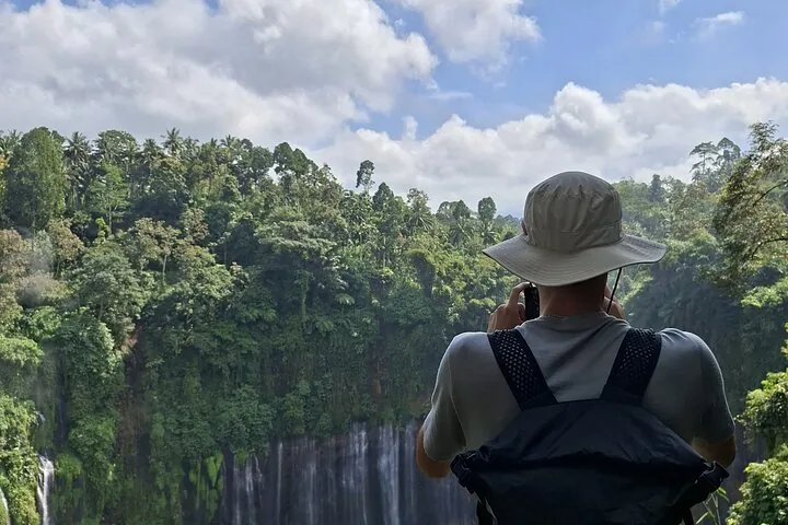 tourist taking a photo of the Tumpak Sewu Waterfall from a viewpoint